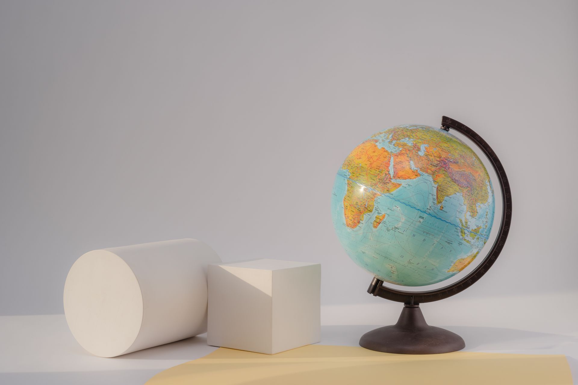 A globe next to abstract geometric shapes on a light background, ideal for education or design concepts.