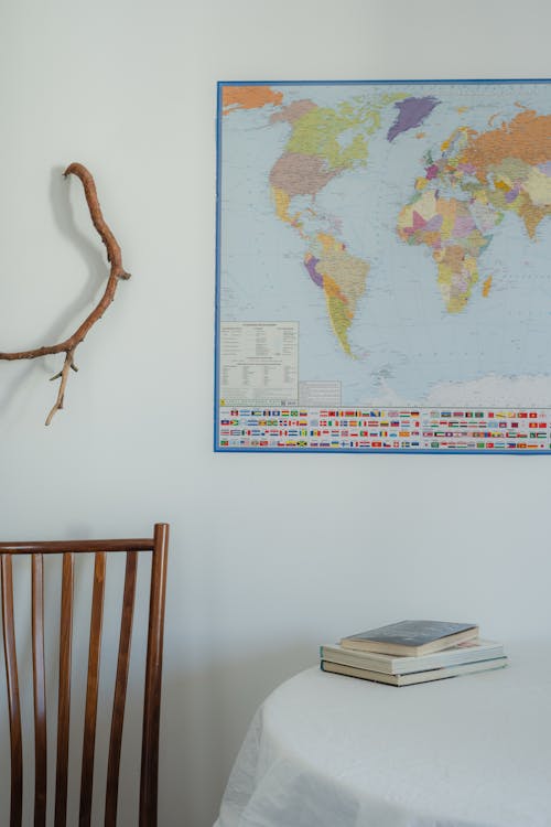 Stacked Books on the Table and a World Map on the Wall
