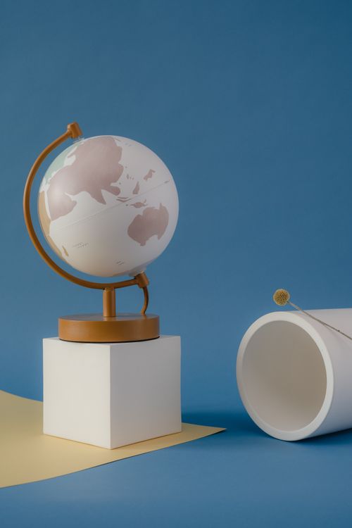 Free A minimalist still life composition featuring a globe and geometric shapes on a blue backdrop. Stock Photo