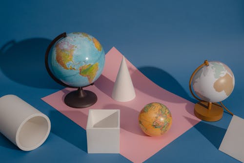 Globes on a Stand on the Blue Background with a Piece of Paper
