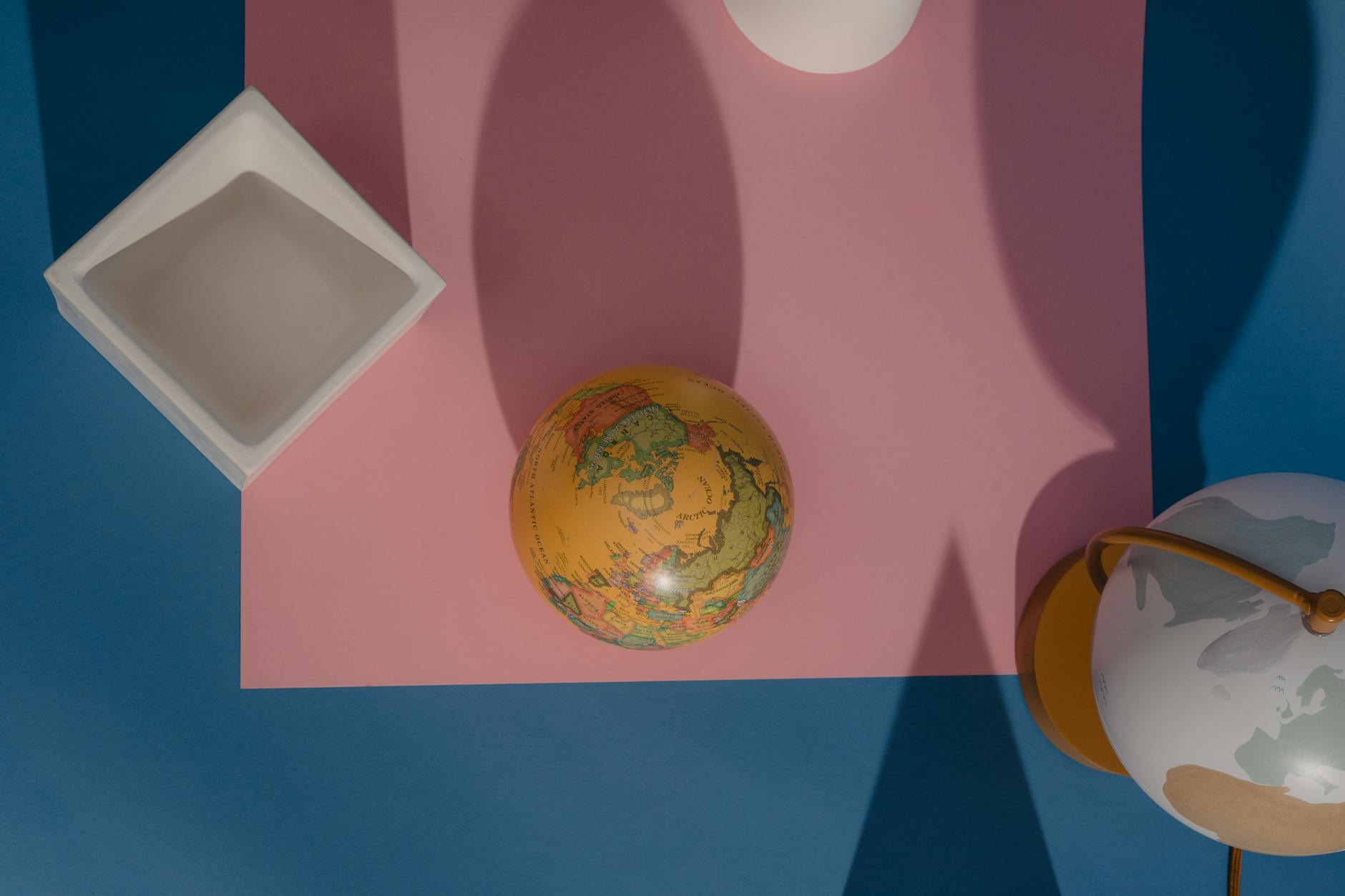 https://www.pexels.com/photo/top-view-of-a-yellow-globe-on-pink-surface-7635005/