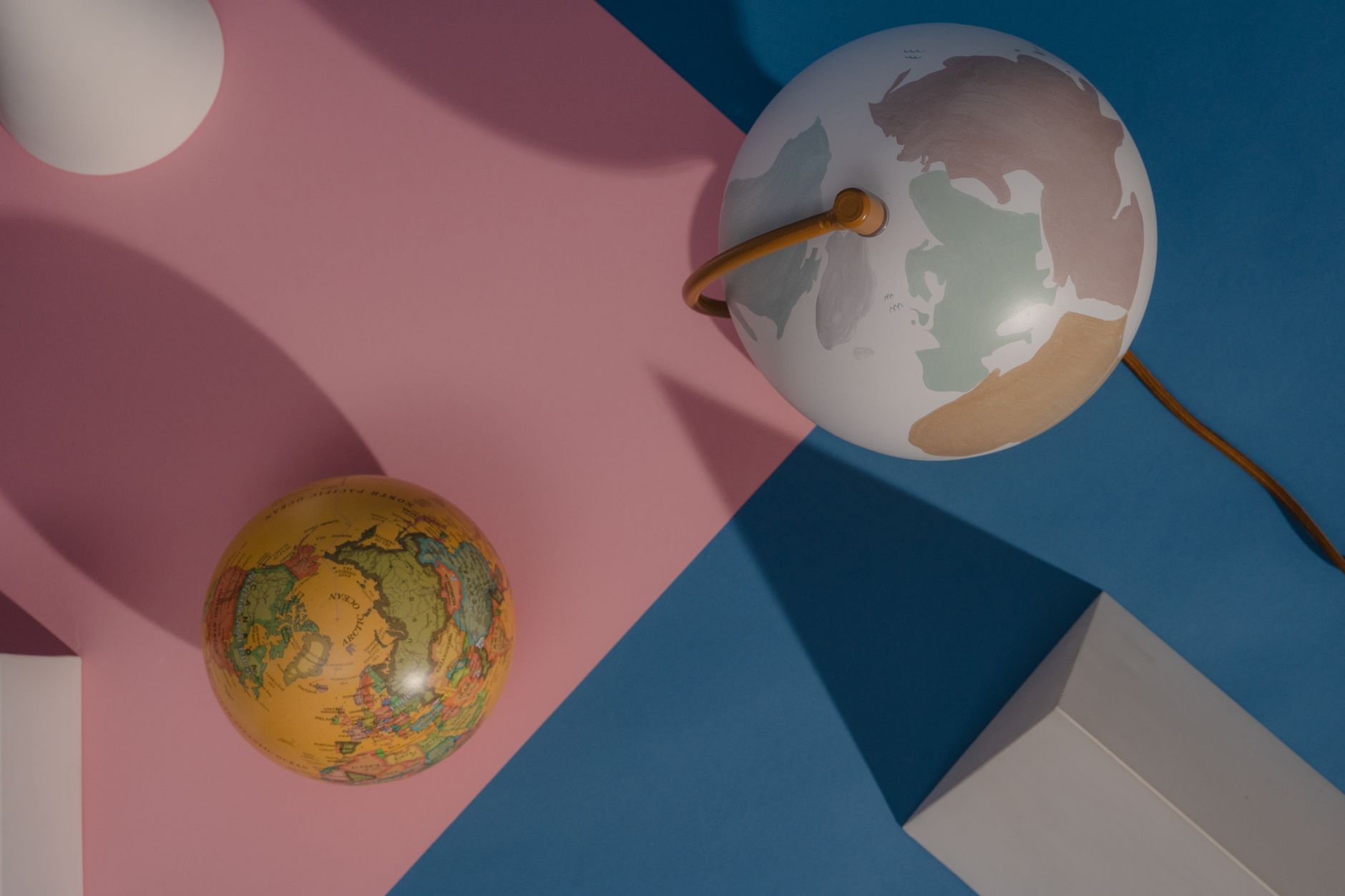 Stylized image featuring two globes with geometric shapes against a pink and blue background.