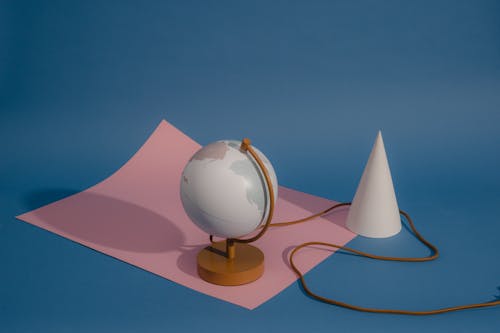 A Lamp Globe near the Paper Cone on the Blue Background