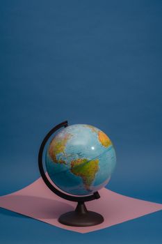 A vibrant globe showcased against a blue backdrop on pink paper, highlighting the Americas. 7635014