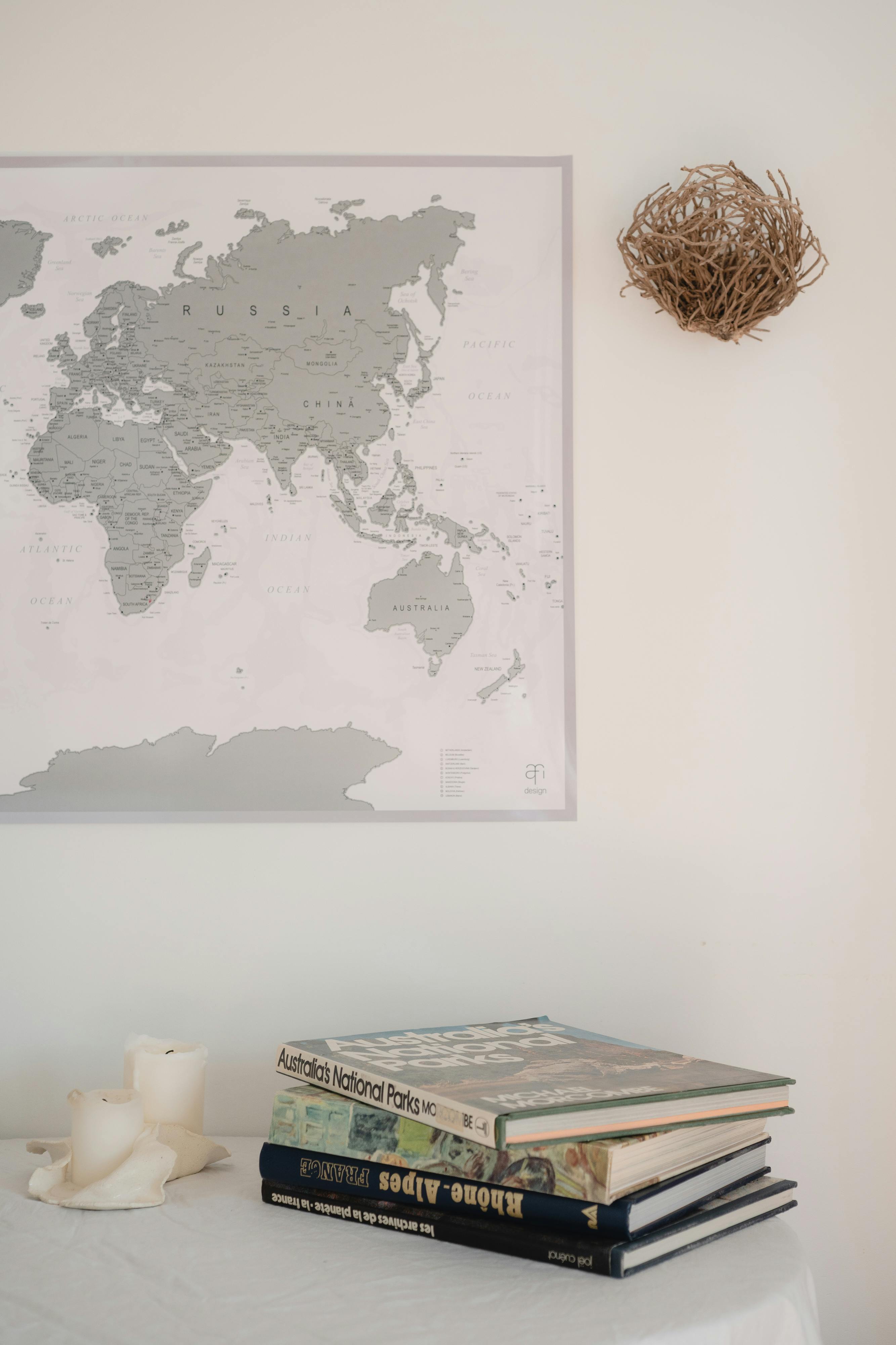 Free A minimalist interior featuring a world map and a stack of nature books on a table. Stock Photo