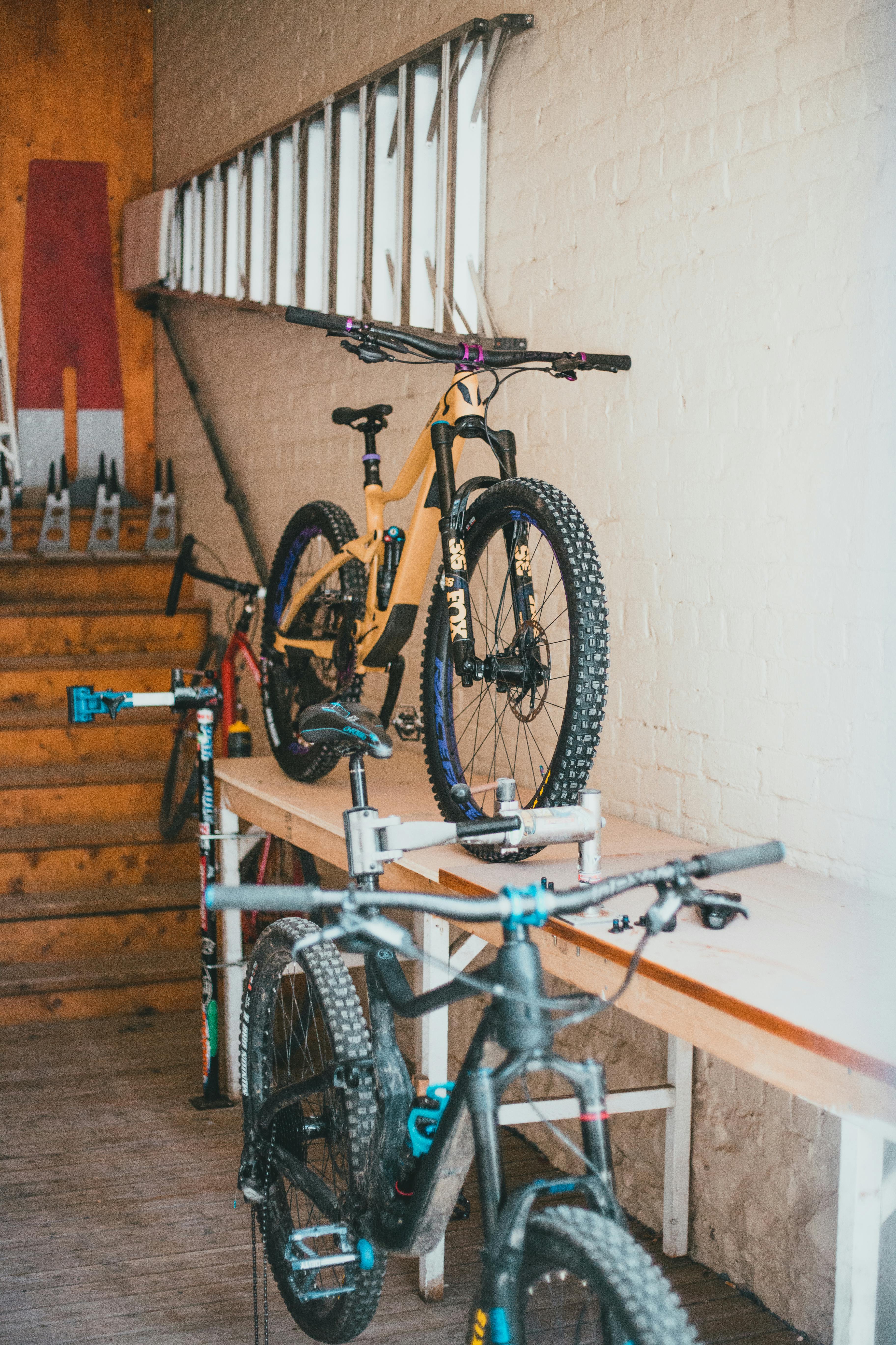 Discover a detailed indoor scene showcasing parked high-end mountain bikes on a wooden table.