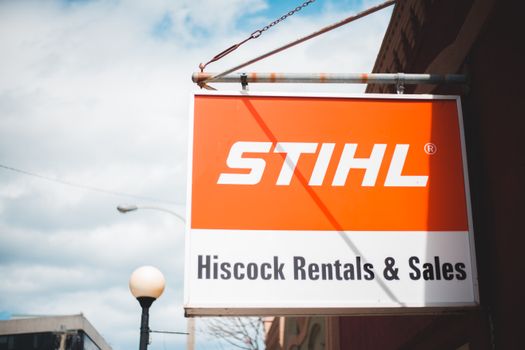 Outdoor STIHL sign in urban environment with clear blue skies and visible streetlamp. 7635134