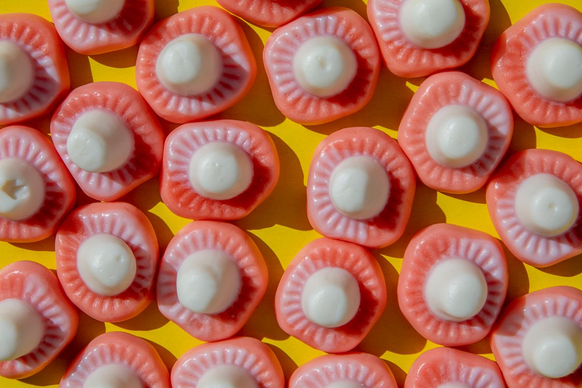 Close-up of pink and white candies arranged on a bright yellow background, creating a colorful visual impact.