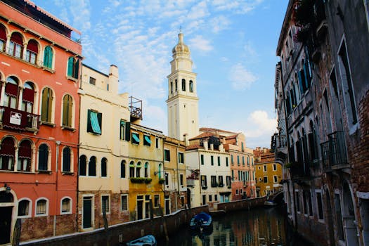 沿着威尼斯运河探索，两侧是历史建筑和蓝天映衬下的教堂塔楼