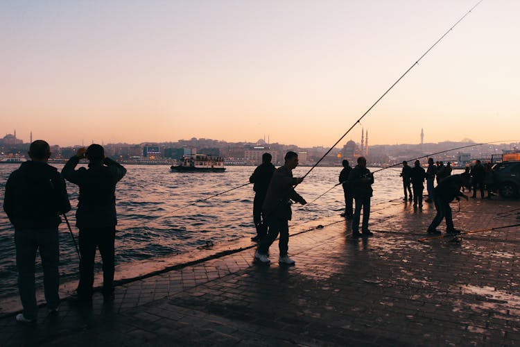 Group Of People Fishing On Riverbank