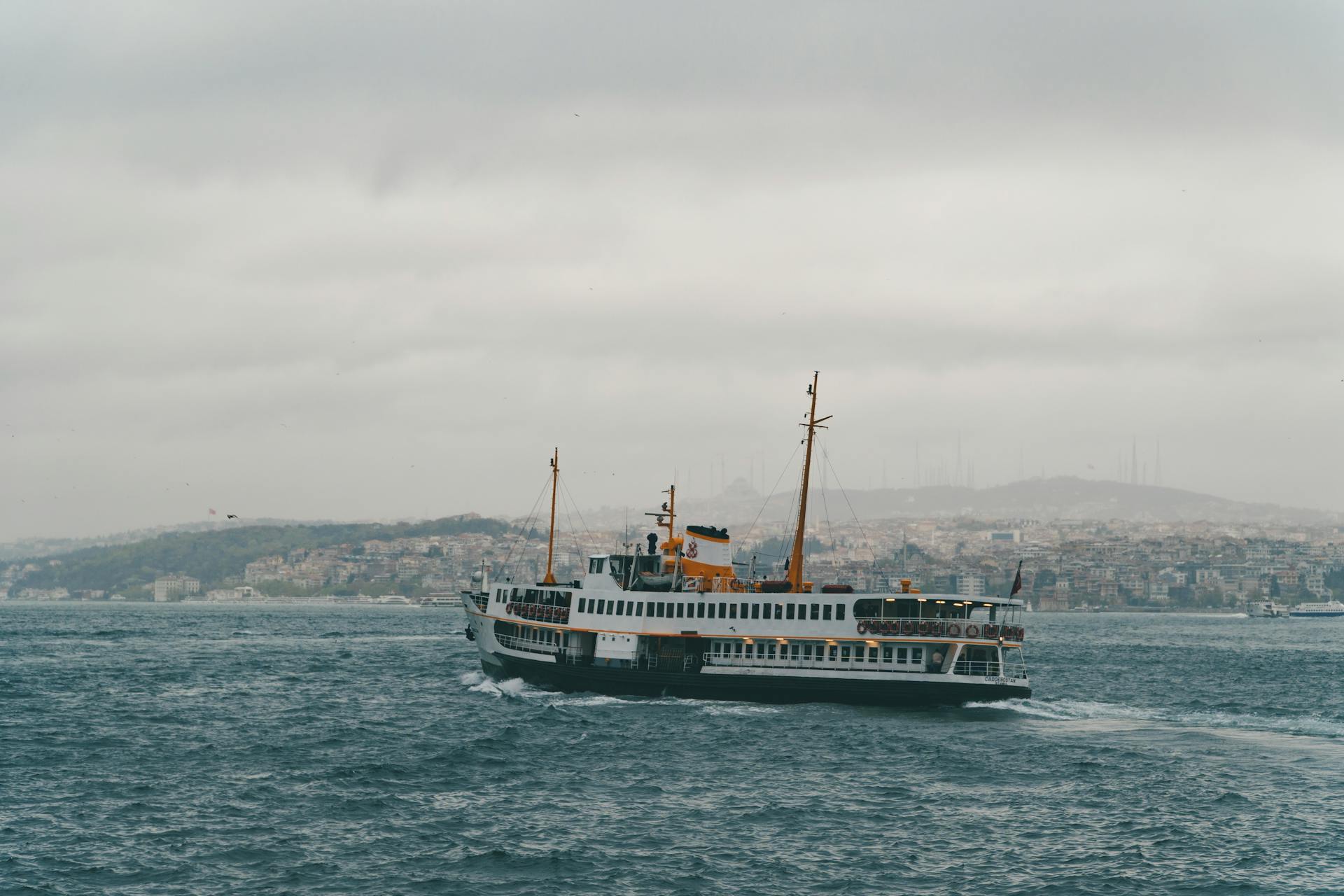 Scenic view of a ferry boat sailing on the Bosphorus with Istanbul skyline in the background.