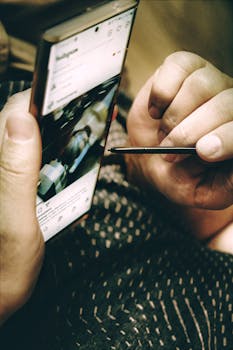 Close-up of hands using a stylus on a smartphone screen, vertical shot.
