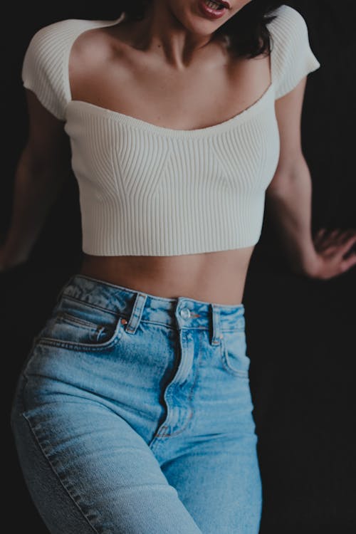 Photo of a Woman Wearing a White Crop Top and Blue Denim Jeans 