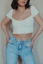 Woman in White Crop Top and Denim Jeans with Her Thumbs in Her Pockets