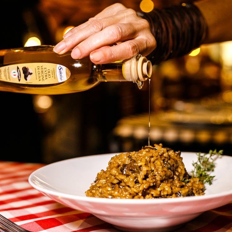 Close Up Shot Of A Person Pouring Oil On Food