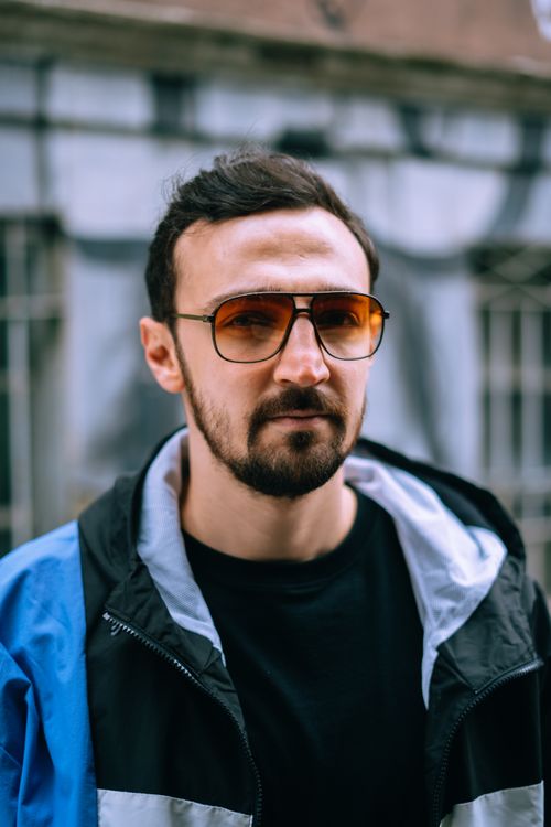 Free Close-up portrait of a bearded man wearing sunglasses and a blue jacket, outdoors. Stock Photo