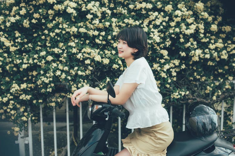 Woman In White Top Sitting On Moped 