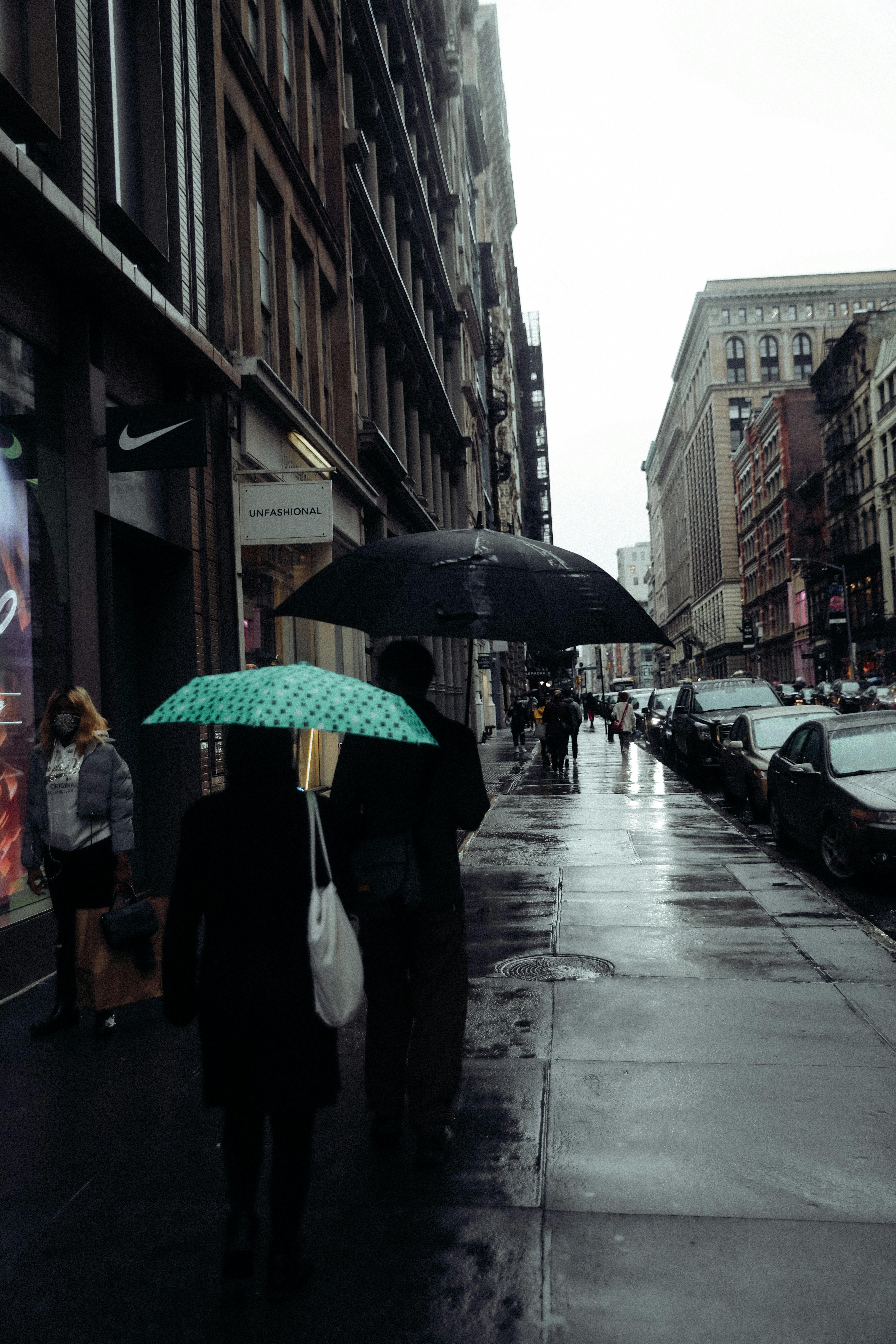 People with umbrellas walking on city street in rainy day · Free 
