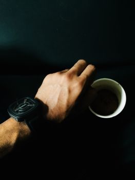 一个人在室内拿着咖啡杯，戴着时尚手表拍照