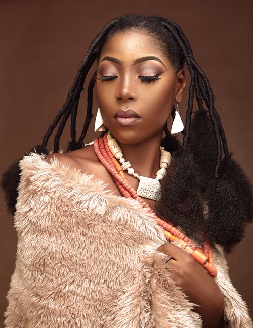 Free Sophisticated portrait of an African woman with traditional hairstyle, fur coat, and jewelry. Stock Photo