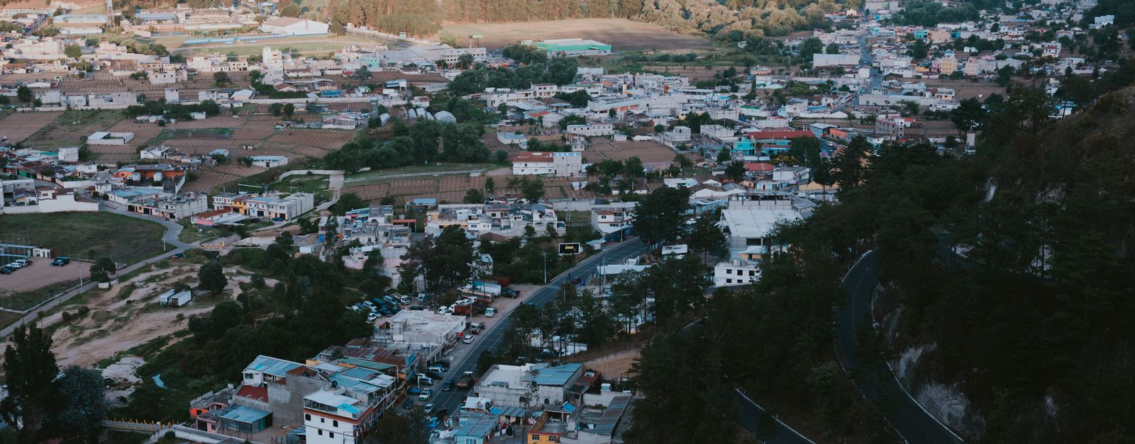 Aerial view of a picturesque mountain town nestled in lush greenery and rugged terrain.