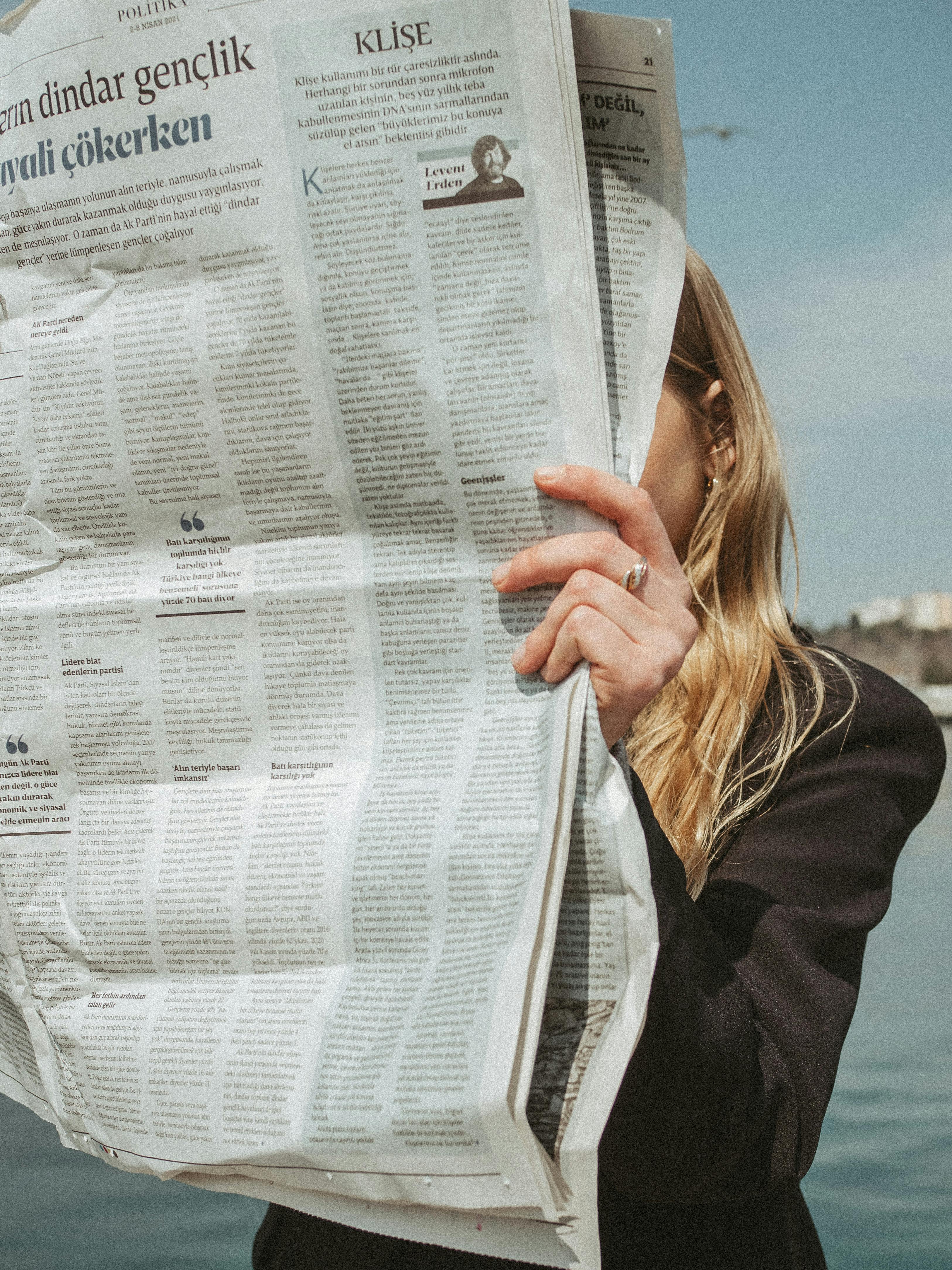 a woman reading a newspaper near body of water