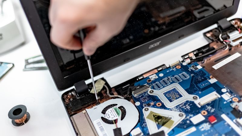technician with a screwdriver working inside an open furnace control panel