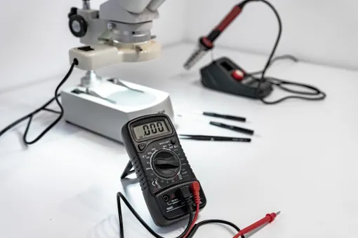Arbeitsplatz mit Multimeter, Mikroskop und Lötkolben