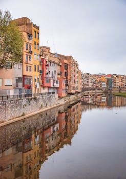 Charming riverside buildings reflecting in the Onyar River, Girona, Spain.