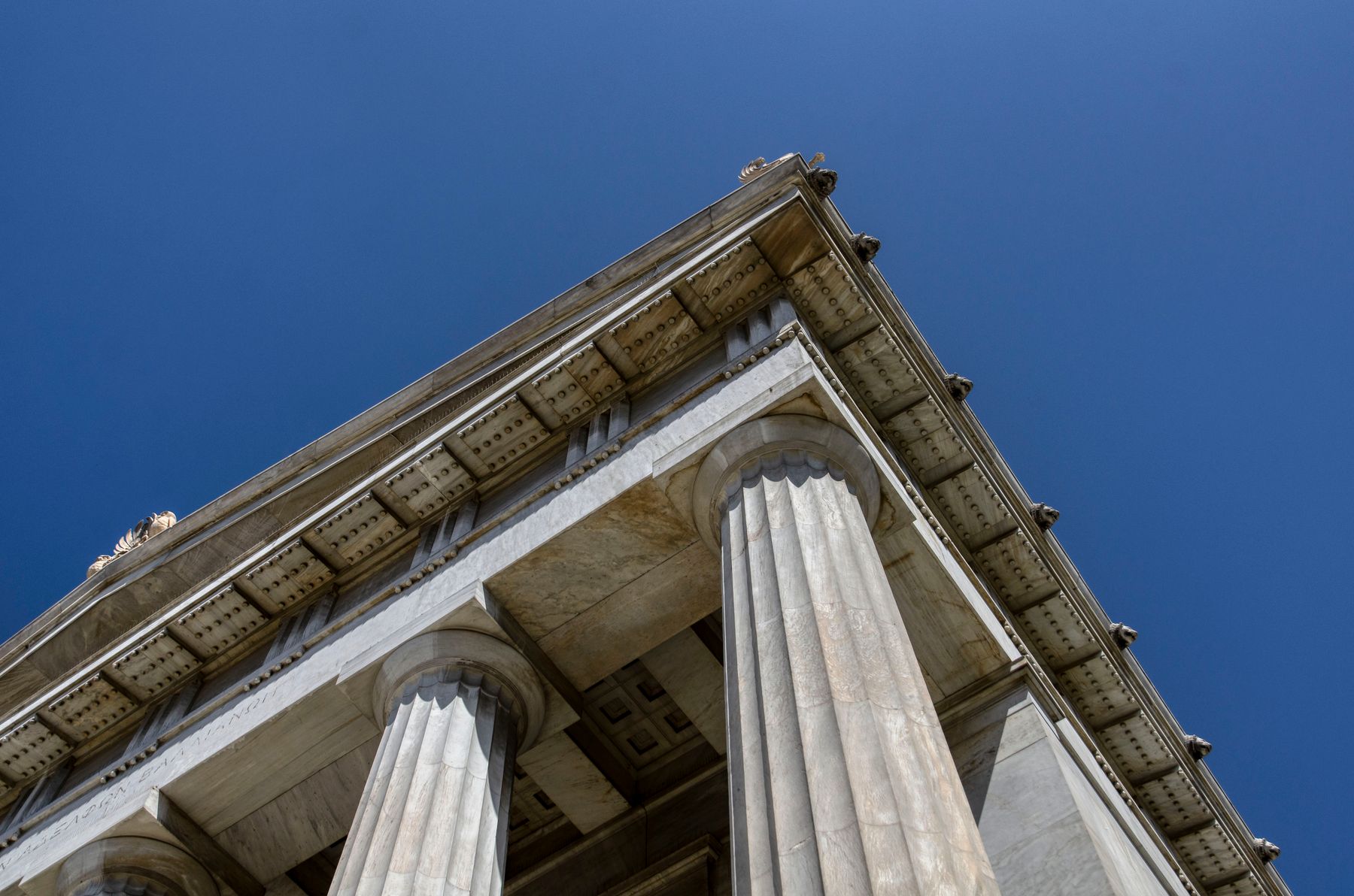 The pediment and fluted stone columns of a classical building against a deep blue sky