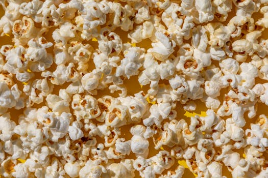 Vibrant close-up of freshly popped popcorn kernels on a yellow background, perfect for snack-themed visuals.