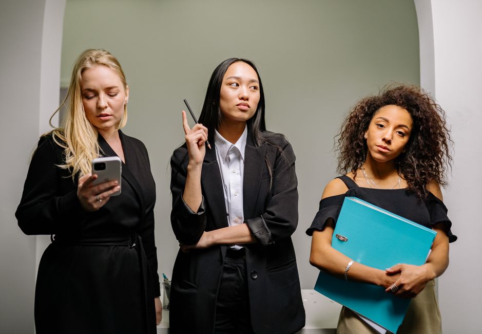 Tres mujeres de negocios diversas en atuendos profesionales en un entorno de oficina.