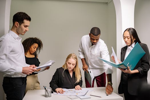 Diverse team working together in an office setting, reviewing documents and collaborating on projects.