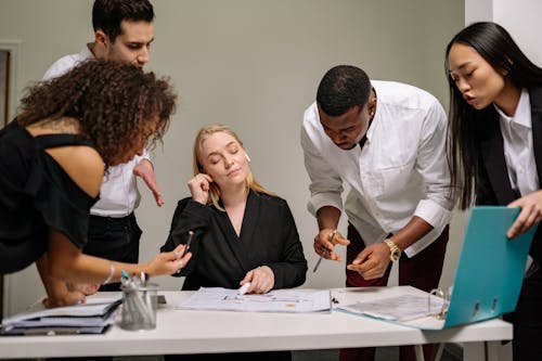 Free Group of People Standing Beside the Woman Sitting at the Desk Stock Photo
