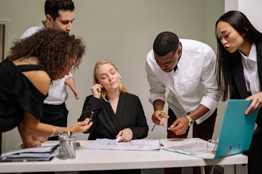 Group of colleagues working together in an office setting, discussing documents and ideas.