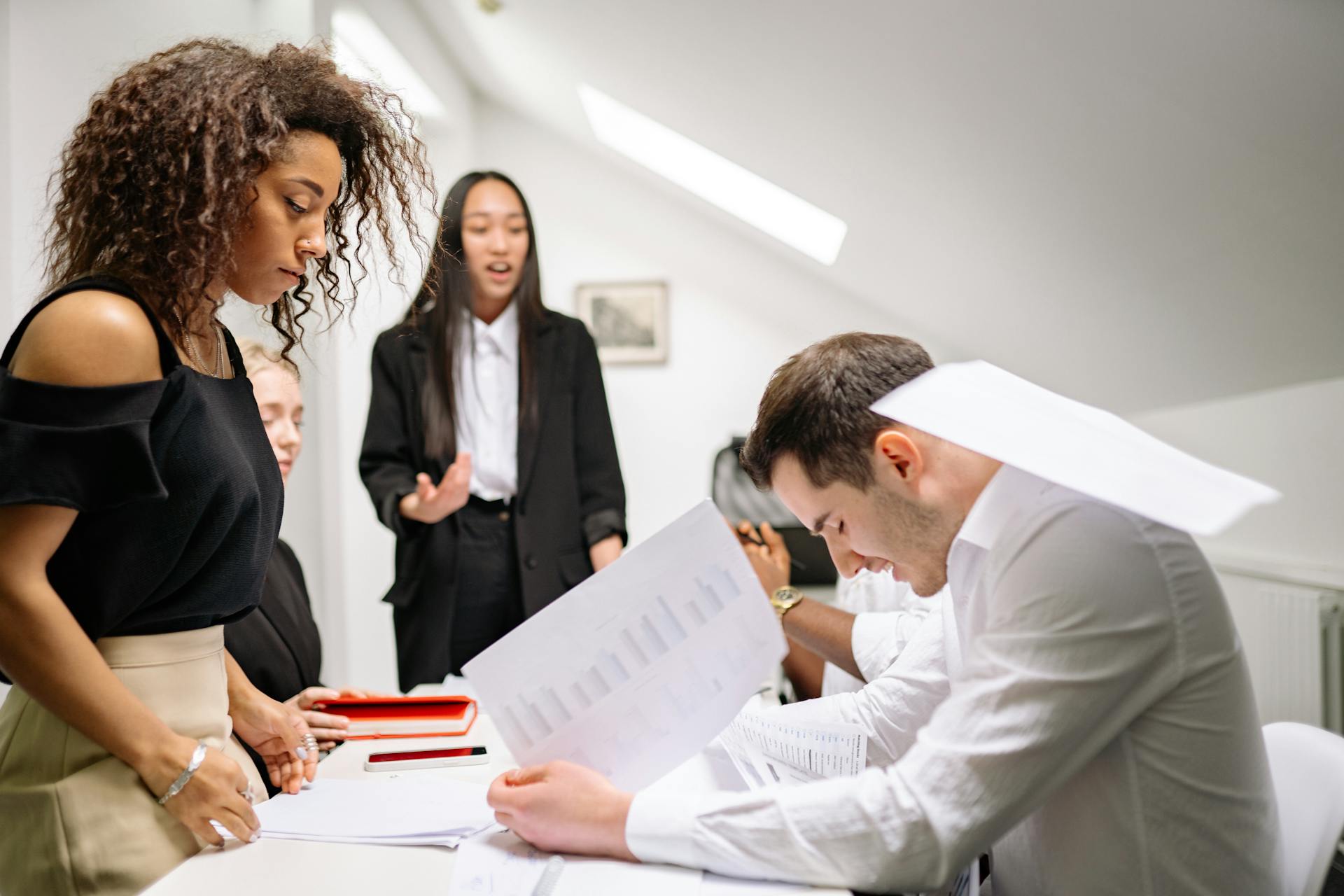 A diverse group of business professionals engaged in discussion and teamwork in a contemporary office.