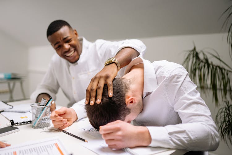 A Coworker Touching An Overworked Person's Head