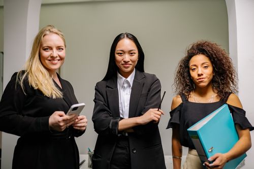 Free Three diverse women confidently posed in a modern office space. Stock Photo