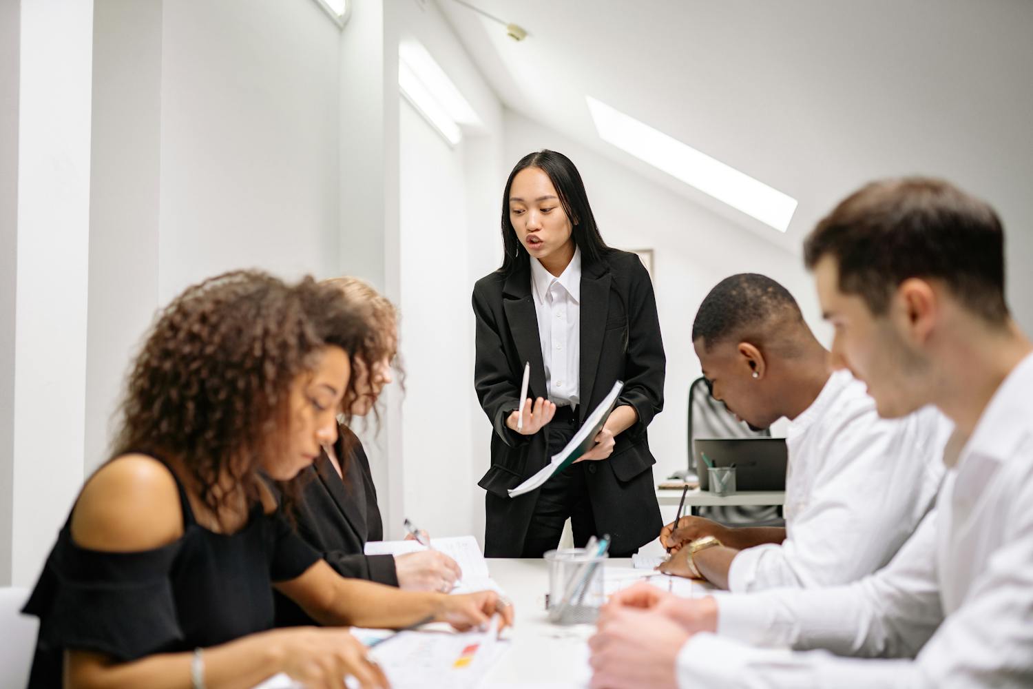 A diverse group of business people collaborating in an office meeting, led by a woman.