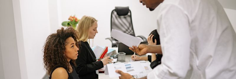 An office meeting where a man argues with a woman over documents, causing tension.