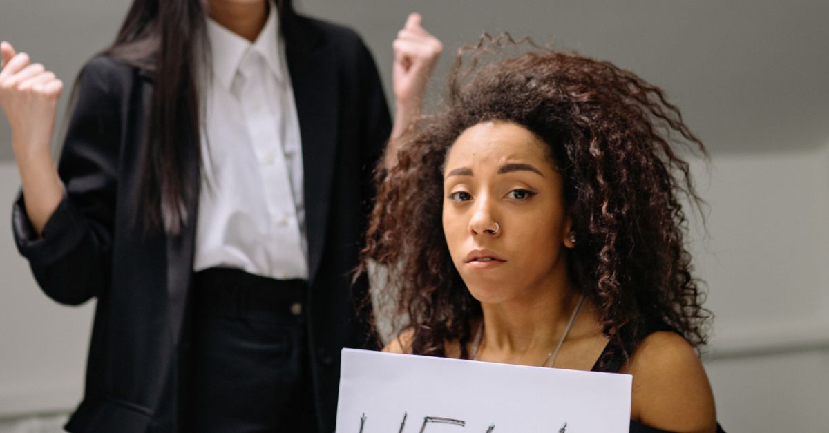 Photo by Yan Krukau A woman holding a help sign, depicting workplace harassment in an office setting.