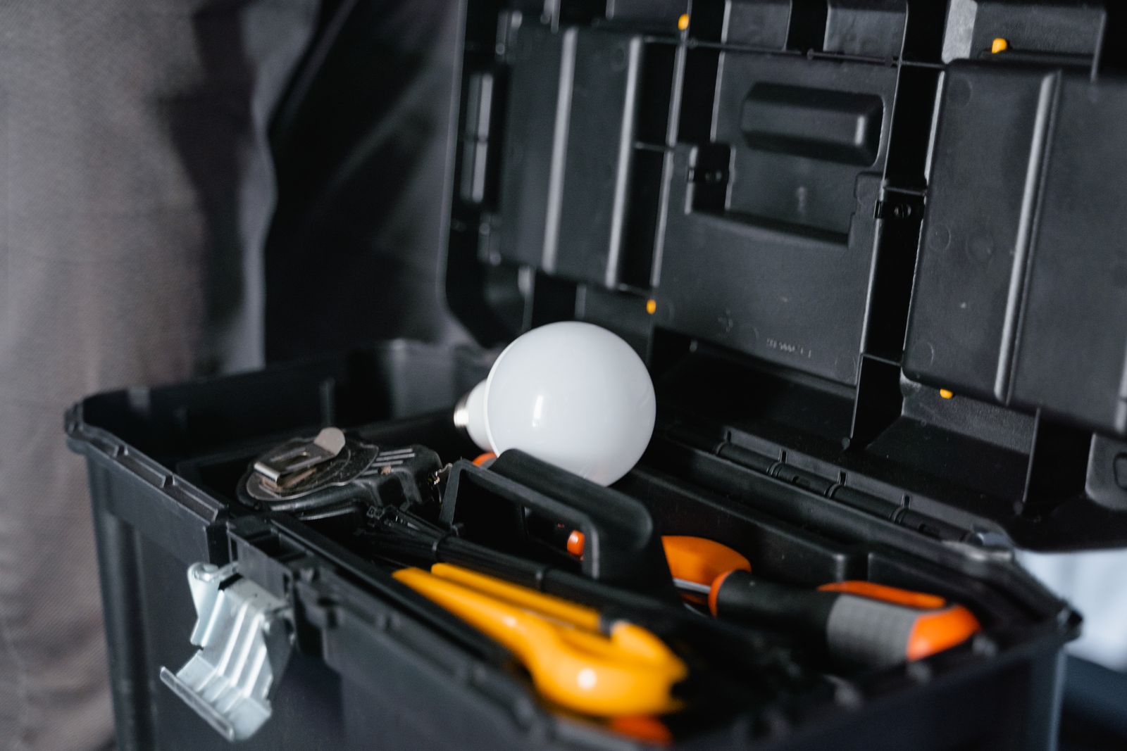An open toolbox containing various hand tools and a light bulb