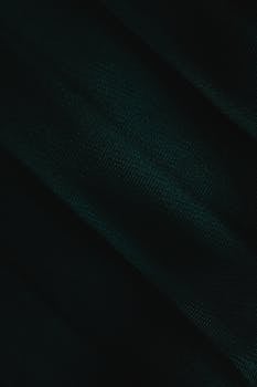A detailed close-up of dark green fabric texture, emphasizing the material's rich color and fine detail.