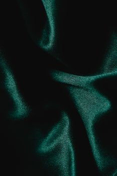 Detailed close-up of creased green fabric, showcasing intricate texture and shadows.
