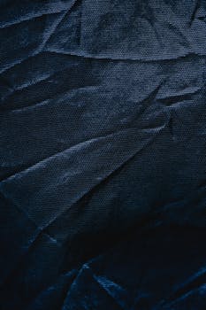 Detailed close-up of creased dark blue textile fabric, ideal for backgrounds and design elements.