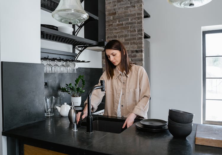 A Woman Washing Dishes On The Kitchen Sink