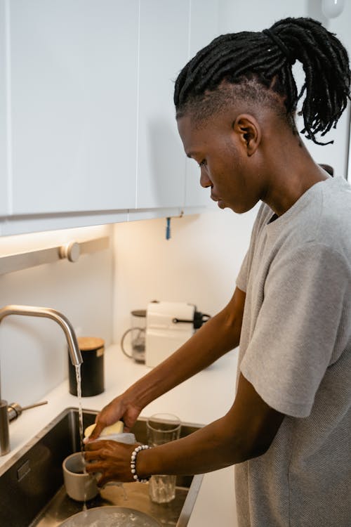 A Man in Gray Shirt Washing Dishes in the Kitchen