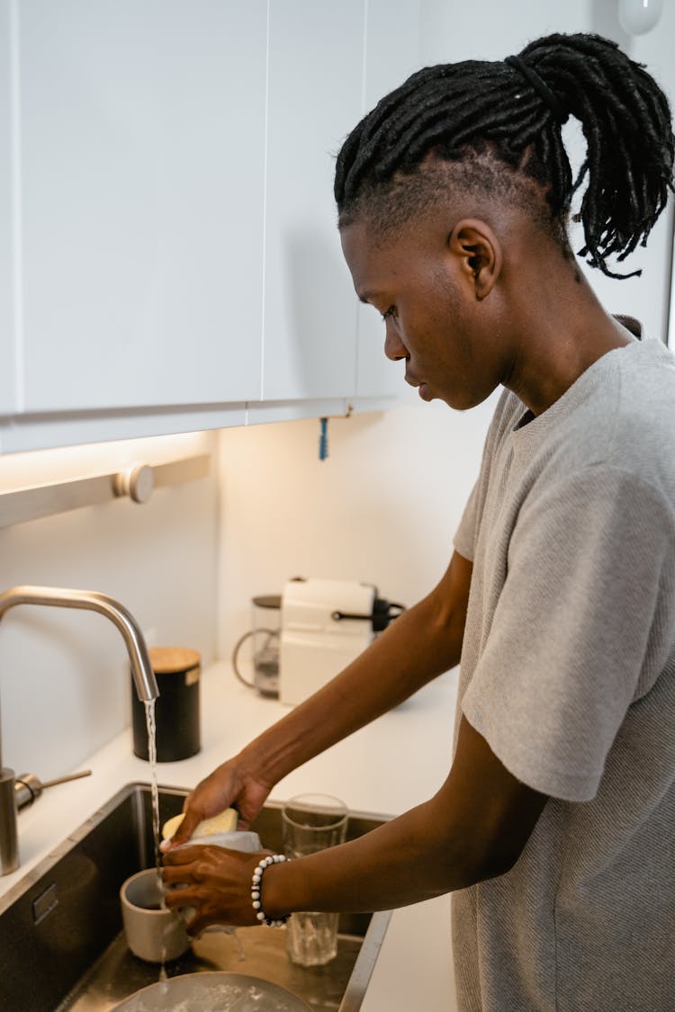 A Man In Gray Shirt Washing Dishes In The Kitchen