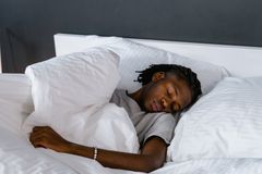 An adult sleeping peacefully on a bed with white pillows and linen.