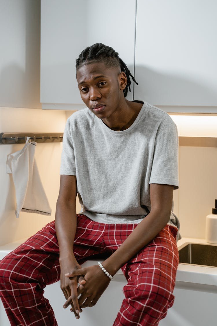 A Man In Gray Shirt And Plaid Pajama Sitting On The Countertop